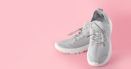 New comfortable sneakers, gray sports shoes with laces on a colored pink background with copy space. Fashion stylish, beautiful women's shoes for women and teenagers. minimalism nobody