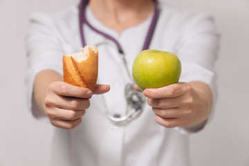 The concept of weight loss of food choice. A nutritionist holds bread and an apple in a woman's hands