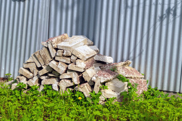 old concrete blocks on grass near a metal fence