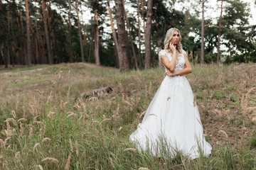 Beautiful blonde bride in the long wedding dress standing in the park