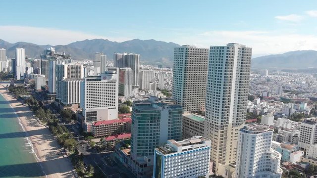 Aerial drones take a beautiful view of the city from a bird's eye view with skyscrapers or tall buildings against the backdrop of a beautiful blue sea. 4K.