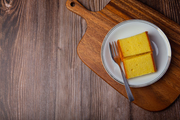 Plate with delicious sliced butter cake on wooden background.