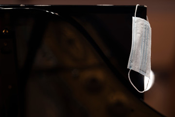 Fototapeta na wymiar A face mask hanging from the lid of a grand piano representing performance restrictions during a pandemic