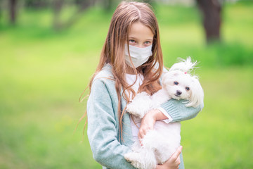 Little girl with dog wearing protective medical mask for prevent virus outdoors in the park