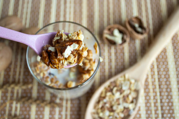 Muesli with nuts in a glass with a spoon. Healthy and healthy food on a wooden table