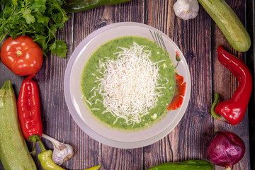 Gourmet spinach soup grated cheese in a bowl, top view