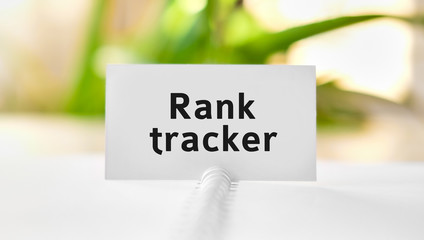 Rank tracker - business concept text on a white notebook and green flowers