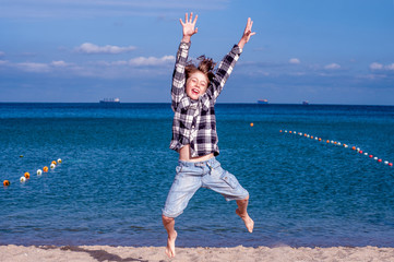 Joyful boy fun jumping on the background of the sea. Travel concept. End of quarantine of coronavirus covid-19. Travel and beach holiday. Vacation. Summer rest