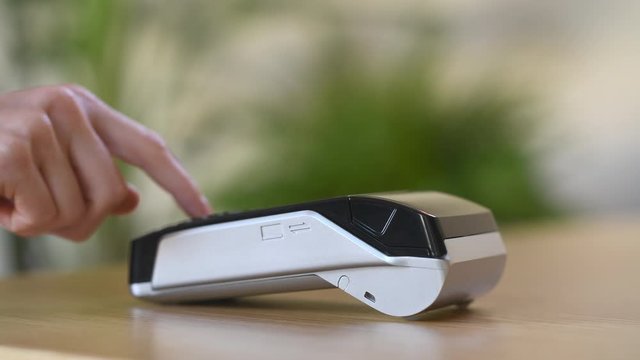 Close up hand of woman paying bill with credit card by contactless. Hand of customer make payment with contactless credit card with NFC technology on terminal device. Closeup of mobile payment.