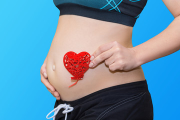 pregnancy, motherhood and maternity concept - happy future mother holding red heart
