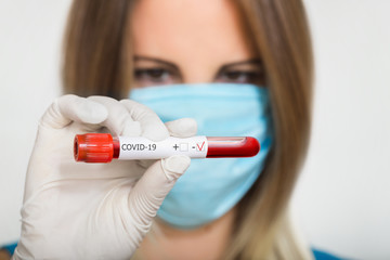 Nurse doctor in medical mask holding test tube with negative coronavirus test blood sample
