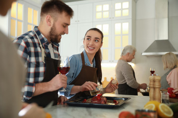 Happy people cooking food together in kitchen