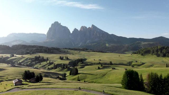 Cyclists riding bicycles at Seiser Alm meadows in Dolomites Italy. Aerial view of travel destination Alpe di Suisi mountain valley in Alps of South Tyrol