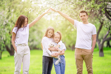 Fototapeta premium Adorable family in blooming cherry garden on beautiful spring day