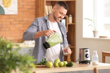 Man with healthy homemade smoothie in kitchen