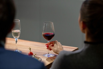 Young girl with a glass of wine at the table with snacks