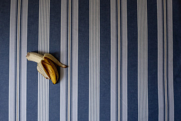 A bitten banana on a blue striped background
