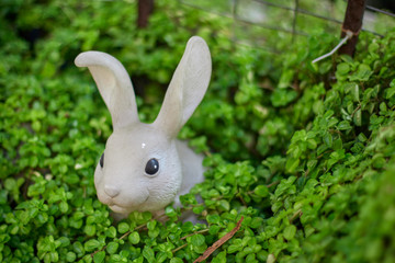 Fake plastic rabbit covered by a plant