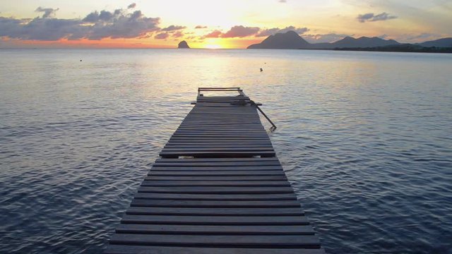 couch&eacute; du soleil sur un ponton de bois au milieu d'un baie de Martinique