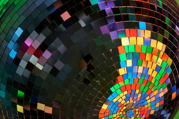 Close crop of a disco ball lit by multiple colored lights