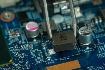 Master tweezers takes a microchip from the laptop's motherboard close up