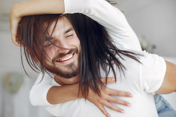 Cute couple in a bedroom. Lady in a white shirt. Pair at home