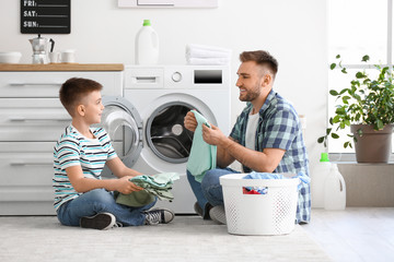 Man and his little son doing laundry at home