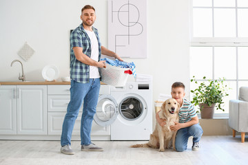 Man and his little son with cute dog doing laundry at home