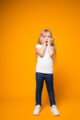Charming long-haired girl child puts her hands to her face and portrays shock. British woman depicts emotions on camera