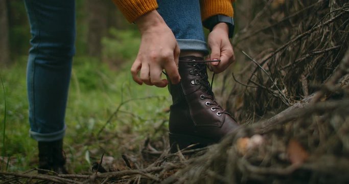 A woman on a trip to the forest ties her shoelaces. Hiking boots in the forest