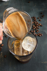 Coffee glass being dropped into a coffee cup full of ice cubes.