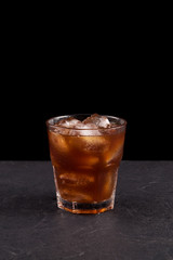 Iced coffee in a transparent glass on a dark background with copy space. Cold summer drink