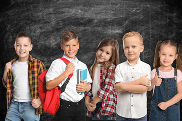 Group of cute school children and chalkboard on background