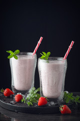  Glass of fresh strawberry shake, smoothie or milkshake and fresh strawberries on table. Healthy food and drink concept with juicy fruits