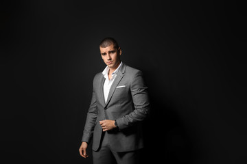 Obraz na płótnie Canvas Handsome young man in elegant suit on dark background