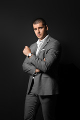 Handsome young man in elegant suit on dark background