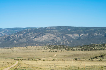 Obraz premium An unpaved, dirt road stretches over miles of land leading to a mountain in rural New Mexico