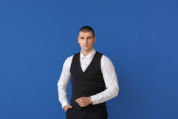 Handsome young man in elegant suit on color background