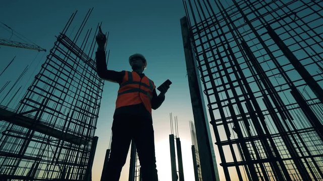A contractor works with his phone while checking building site.