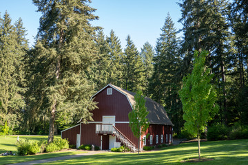 A beautiful shot of a red barn house surrounded by trees in the forest.