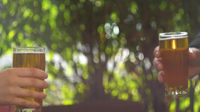 Celebration beer cheers concept - close up hands holding up glasses of beer of people group in outdoor party during their victory competition or successful task meeting vacation