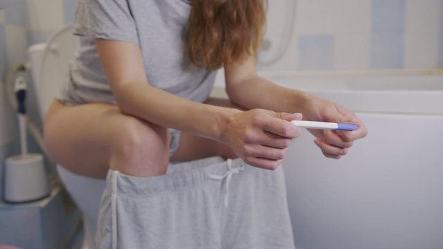 Female holding pregnancy test in hands.