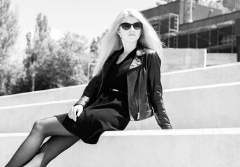 Fototapeta premium A girl with black cat eye glasses frame. Black and white photo, Accessorize your autumn look for ultimate sophistication , posing lady in the part on stairs sitting outside, stylish student