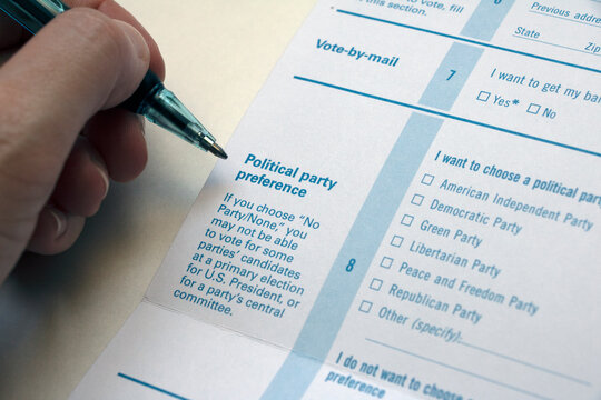 Closeup hand with pen hovering over 'Political Party Preference' section on a Voter Registration form
