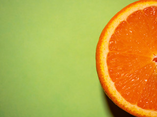 close up of fresh juicy sliced orange on green background. macro top view. summer concept