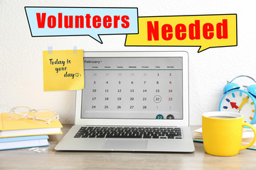 Modern laptop on wooden table in office. Volunteers needed