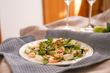 Healthy food: shrimp salad with arugula leaves and cheese on a white plate. Breakfast in bed: shrimp salad.