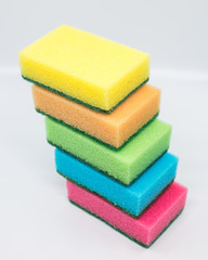 multicolored dishwashing sponges stacked on top of each other over white background