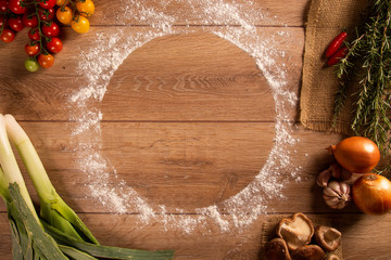 Various vegetables at wooden rustic background with copyspace on round pizza desk. Set of fresh vegetables. Egg, tomatoes, pepper, lettuce, onion, garlic, onion. Pizza ingredients.