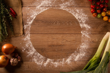 Various vegetables at wooden rustic background with copyspace on round pizza desk. Set of fresh vegetables. Egg, tomatoes, pepper, lettuce, onion, garlic, onion. Pizza ingredients.